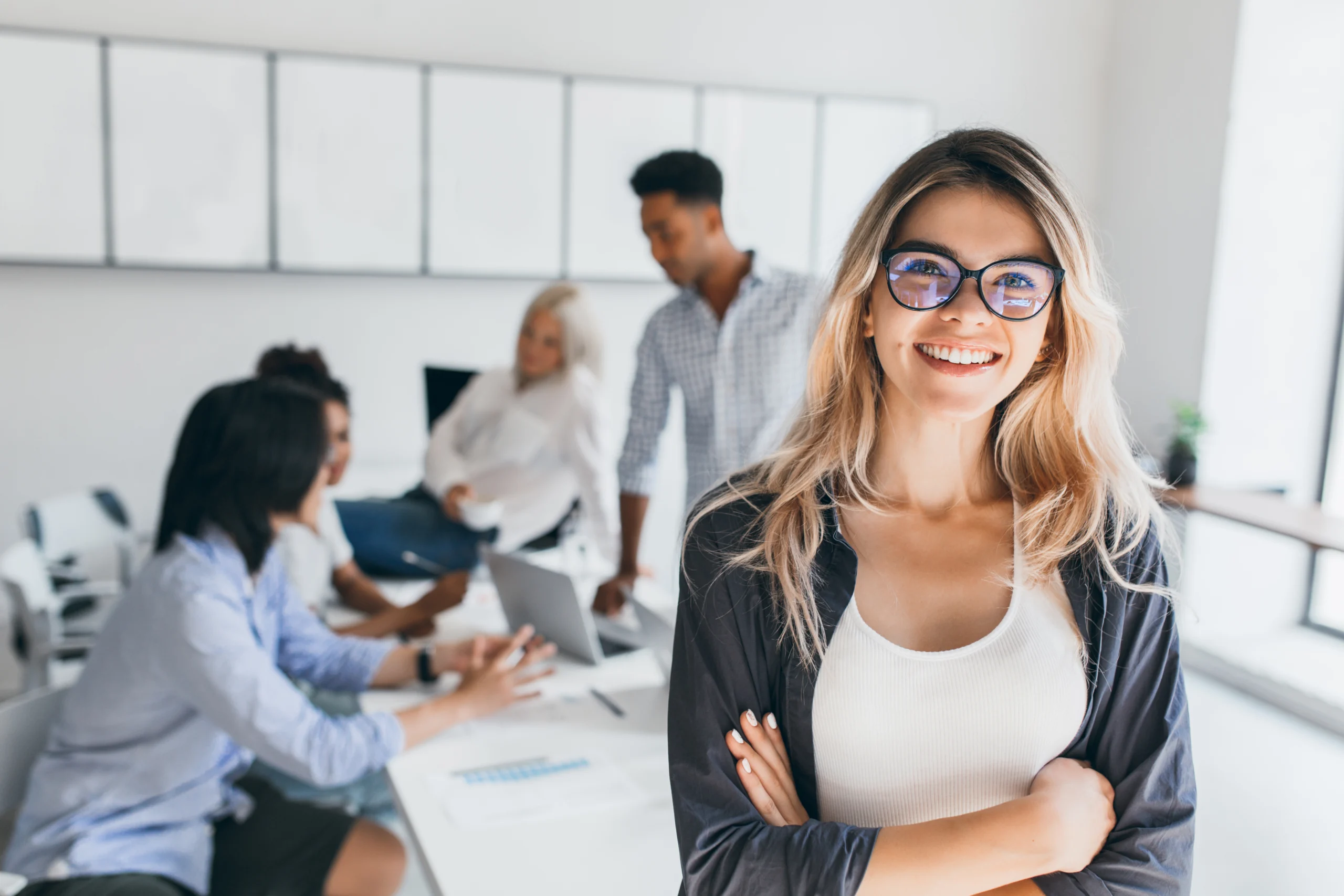 blonde-female-executive-posing-with-smile-arms-crossed-during-brainstorm-with-managers-indoor-portrait-european-student-spending-time-hall-with-asian-african-friends